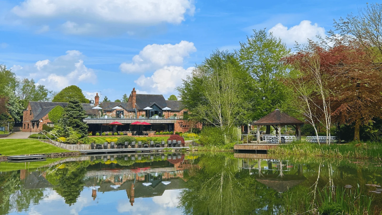 The Oak House restaurant and terrace across the lake at Moddershall Oaks